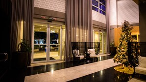 A hotel lobby with a Christmas tree, seating area, and a glass entrance with signage. - Radisson Hotel Alphaville (Barueri)