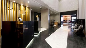 A modern lobby with a reception desk, seating area, and a staircase. - Radisson Hotel Alphaville (Barueri)