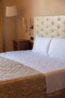Un letto ben rifatto con una testiera imbottita, una lampada da comodino e un comodino in legno.