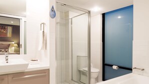 A modern bathroom with a glass-enclosed shower, a white bathtub, and a sink with a mirror. - Oaks Adelaide Horizons Suites (Adelaide)