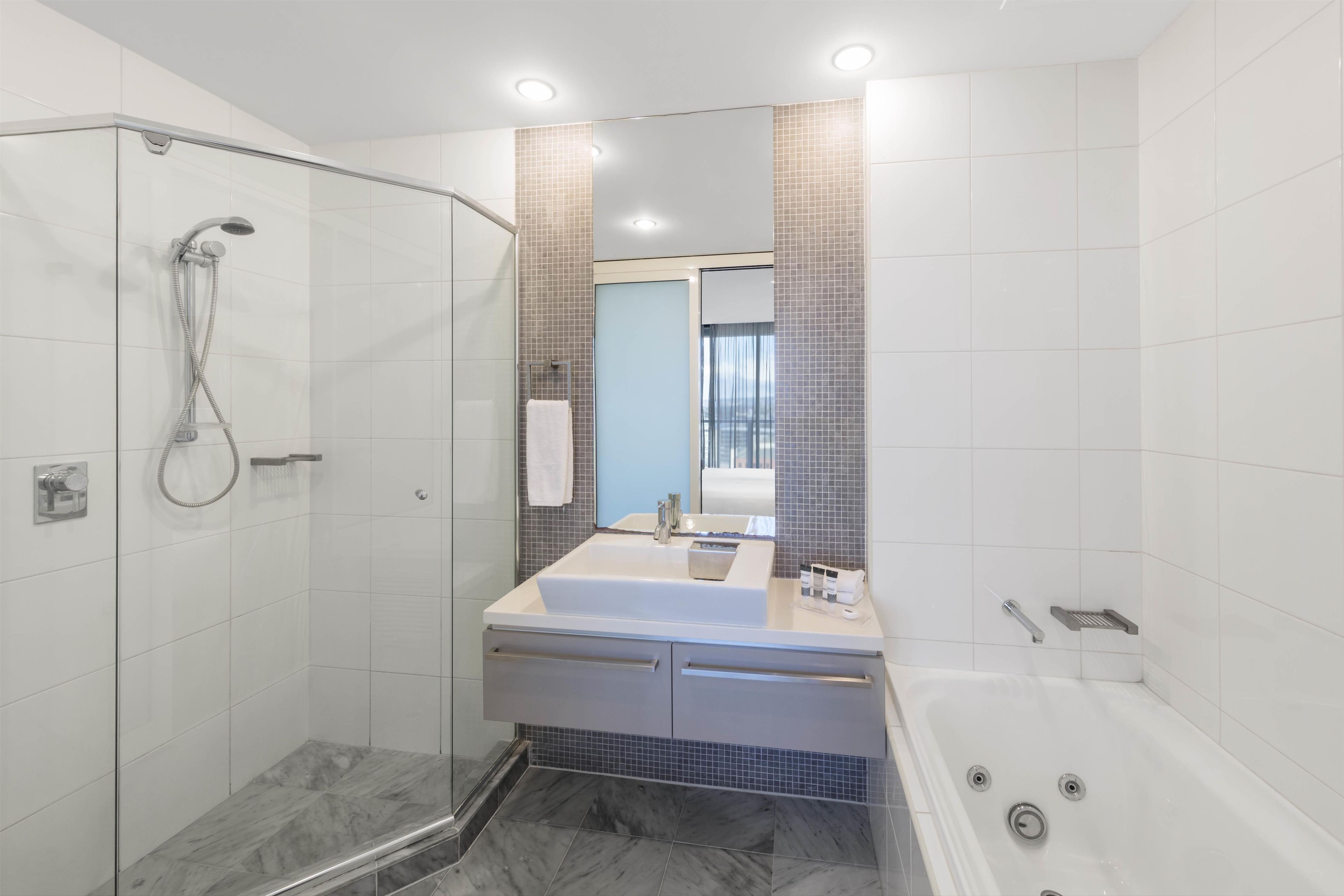 Un baño moderno con cabina de ducha, bañera y tocador con espejo.