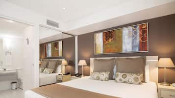 A modern hotel room with a large bed, bedside tables, a mirror, and artwork on the walls.
