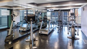 A gym with various exercise equipment, including treadmills and elliptical machines, and a large mirror reflecting the space.