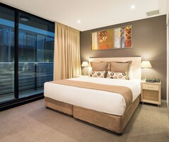 Una habitación de hotel moderna con una cama grande, una mesita de noche, una lámpara y un cuadro en la pared.