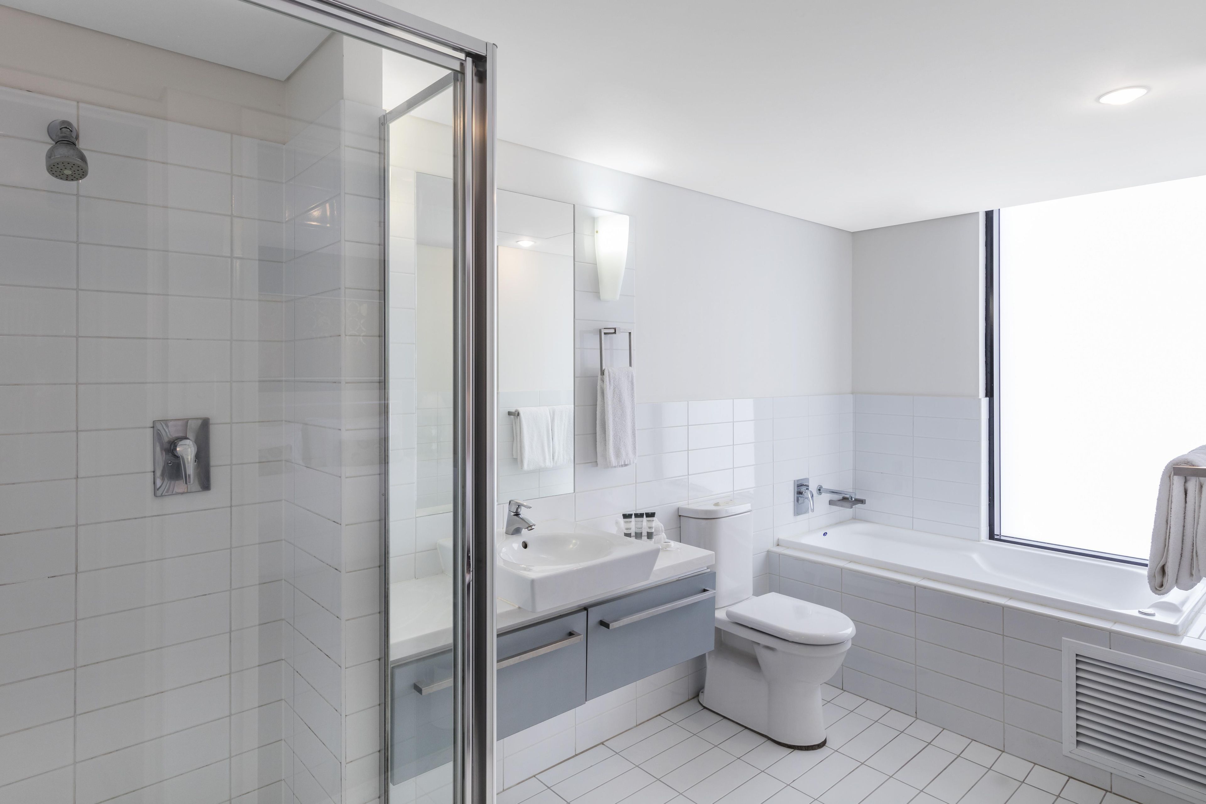 A modern bathroom with a glass shower enclosure, a white sink, a toilet, and a bathtub.