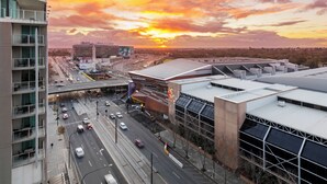 A high-rise building with multiple floors, a rooftop parking area, and a view of a sunset over a cityscape. - Oaks Adelaide Horizons Suites (Adelaide)