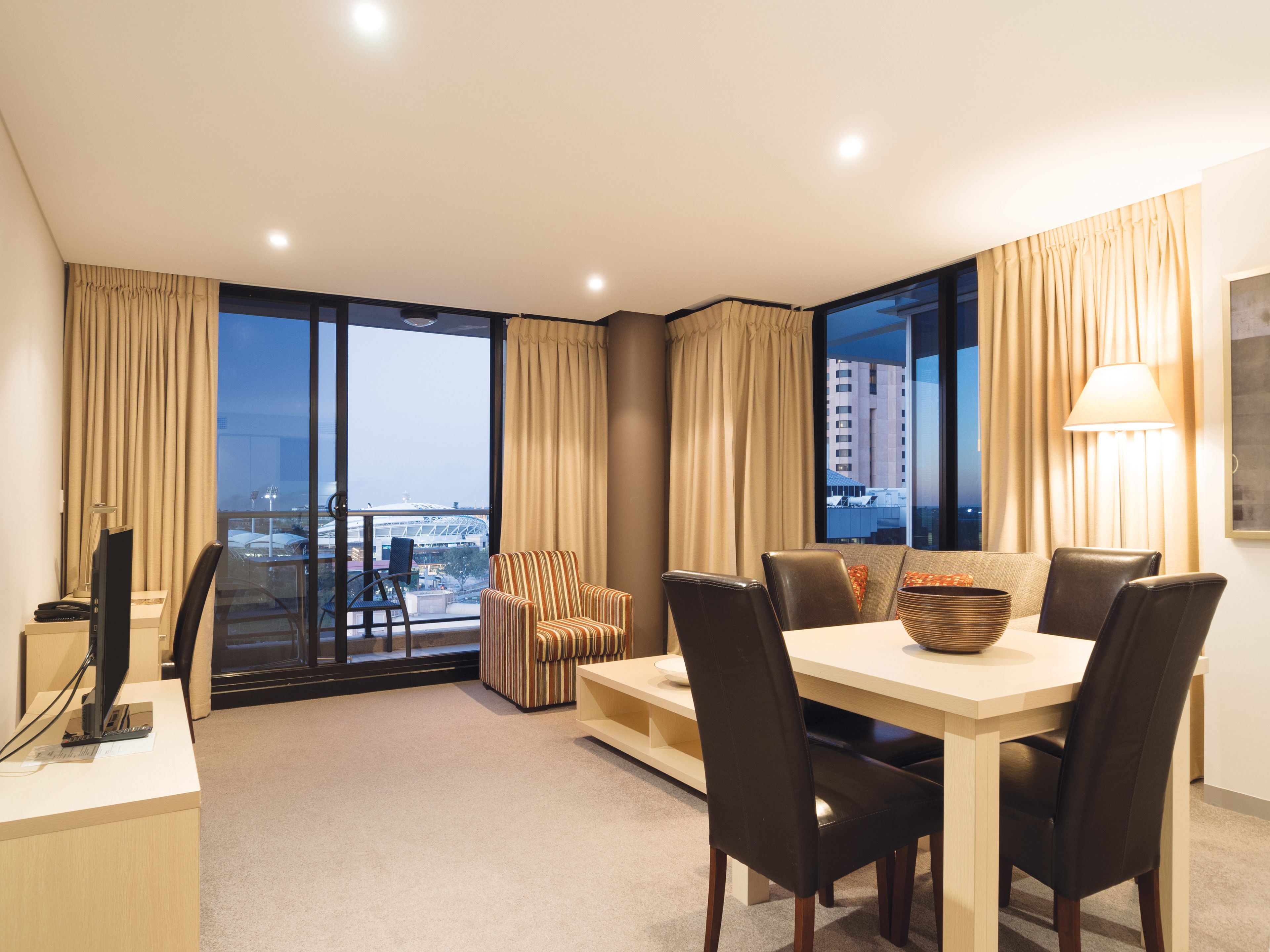 Een moderne hotelkamer met balkon, een zithoek en uitzicht op de stad.