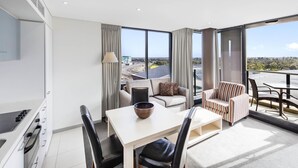 A modern living room with a dining area, large windows, and a view of the cityscape.