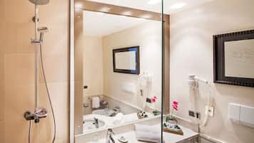 Un baño moderno con ducha envuelta en vidrio, un espejo grande, un lavabo y un secador de pelo en la pared.