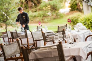 A restaurant with tables set for dining, chairs, and a waiter in the background. - Cosmo Hotel Torri (Vimercate)