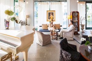Un amplio salón con un piano de cola, asientos cómodos, un ventanal con vistas y una estantería decorativa.