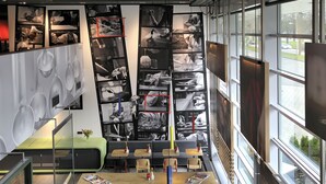Un restaurante moderno con diversas opciones de asientos, incluyendo mesas y bancos, una amplia pared con fotografías en blanco y negro y grandes ventanales que ofrecen vistas al exterior.