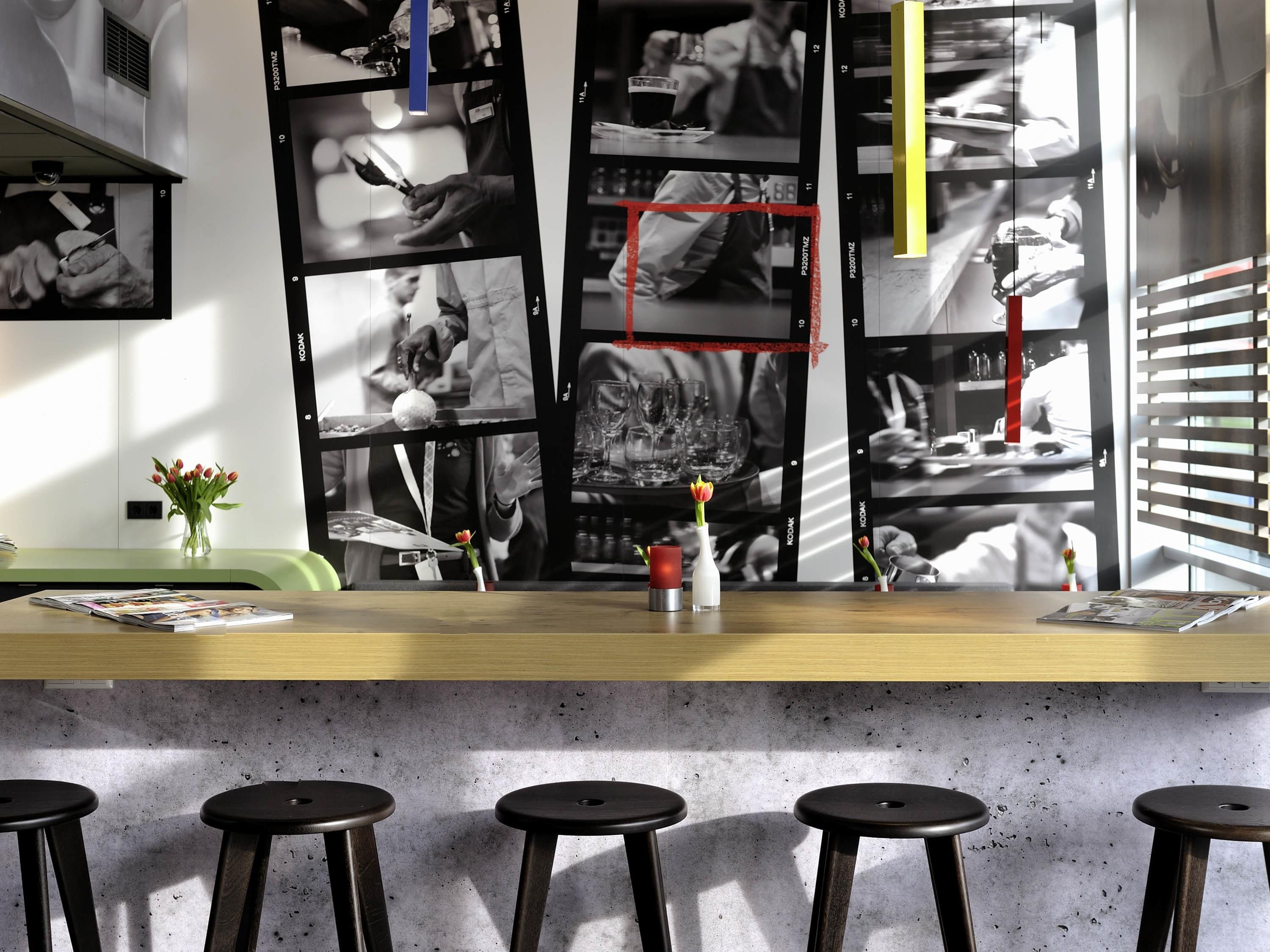 A bar area with a concrete countertop, black stools, and a wall of black and white photographs.