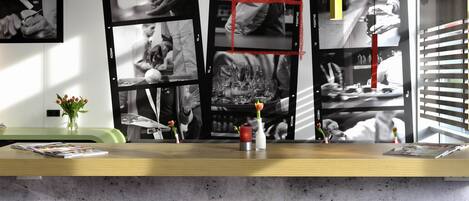 A bar area with a concrete countertop, black stools, and a wall of black and white photographs.