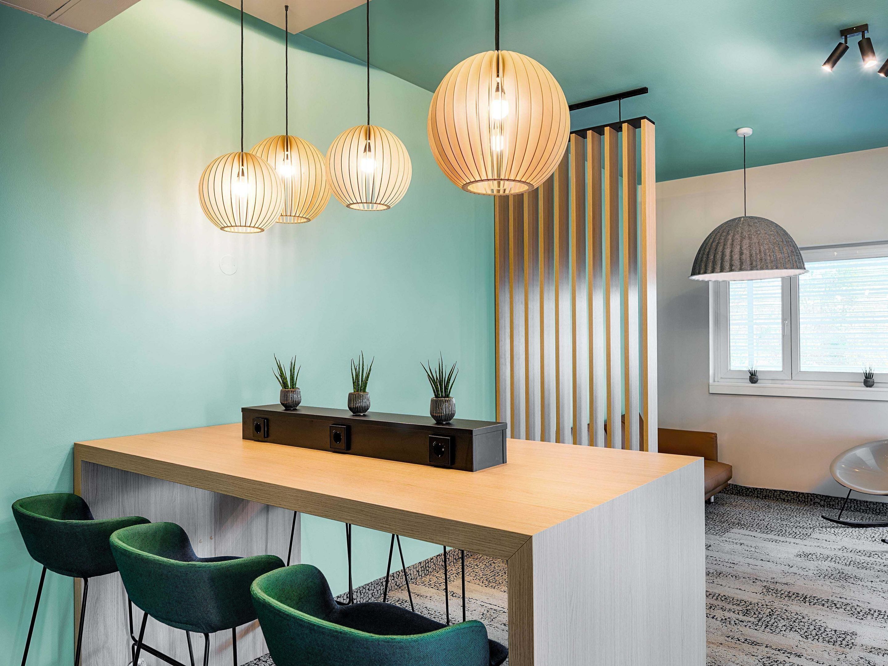 A modern kitchen with a wooden island, bar stools, pendant lights, and a striped curtain.
