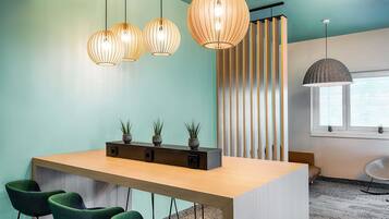 A modern kitchen with a wooden island, bar stools, pendant lights, and a striped curtain.