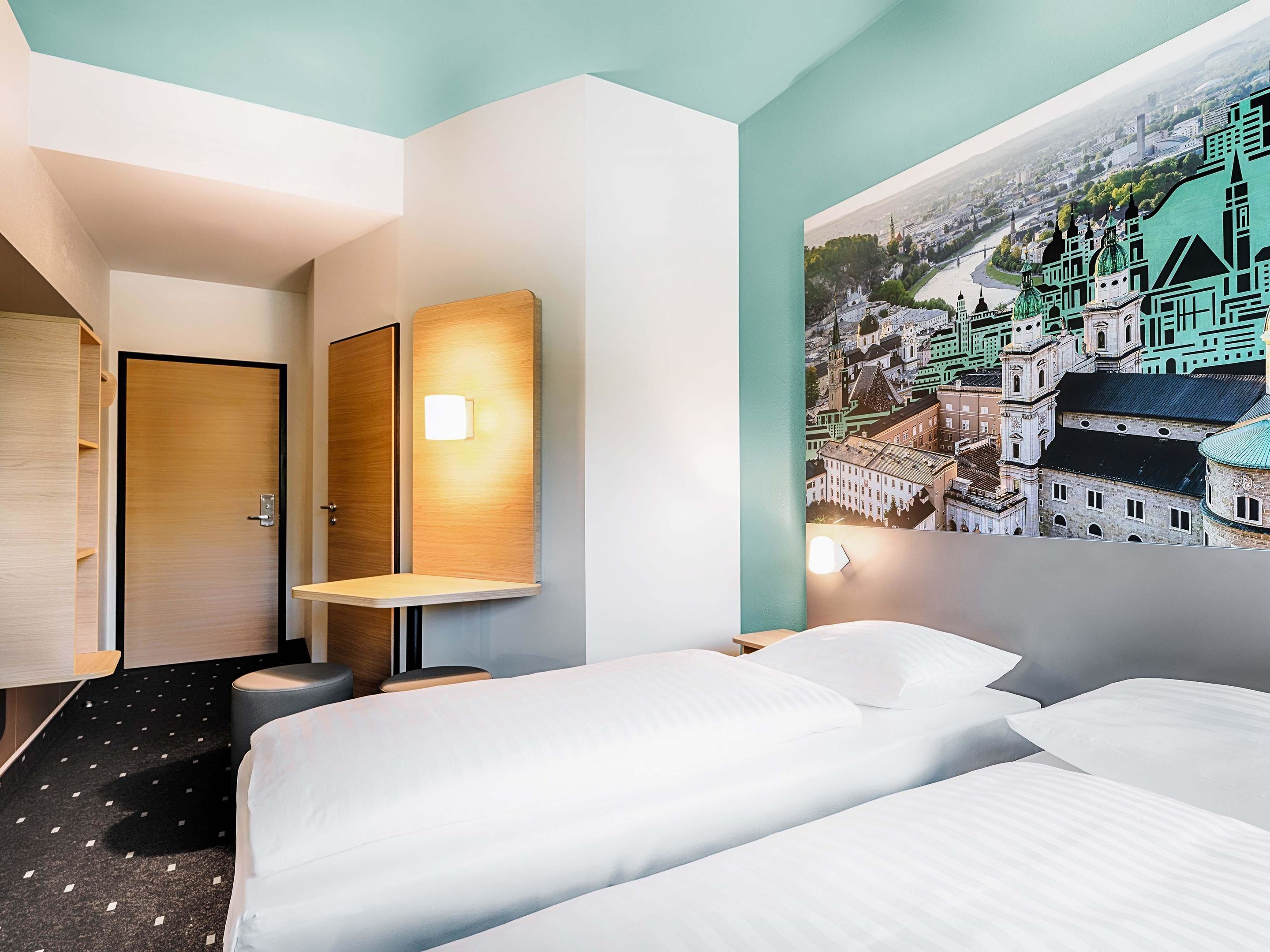 Ein Hotelzimmer mit einem Bett, einem Schreibtisch, einem Stuhl und einer Wandlampe.