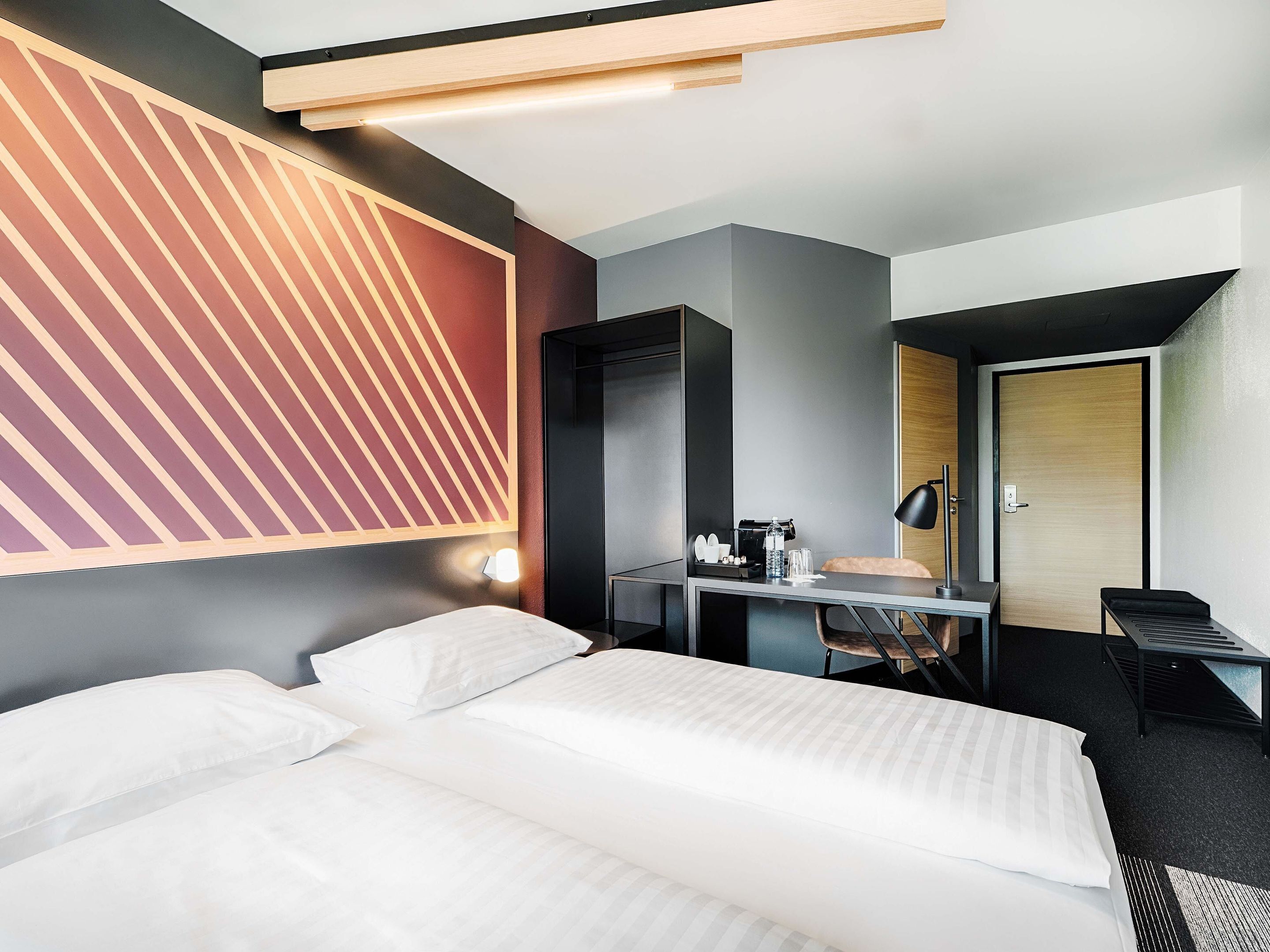 Une chambre d’hôtel avec un lit, un bureau, une chaise et une porte.