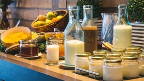 A buffet table with various food items and beverages, including jars of condiments and bottles of milk. - Hotel Novotel Santiago Vitacura (Santiago)