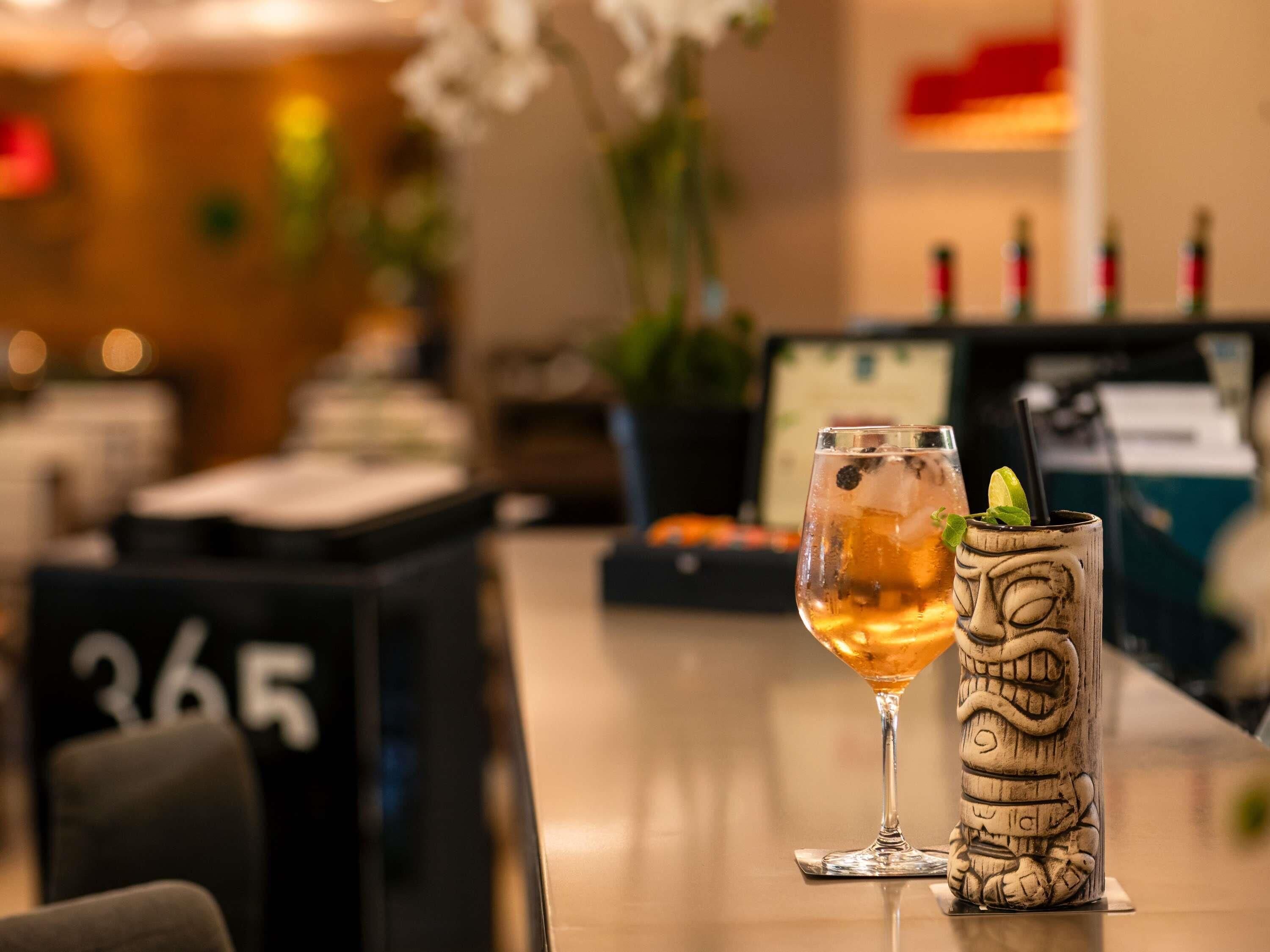 A bar area with two drinks, a number sign '365', and a computer monitor in the background.