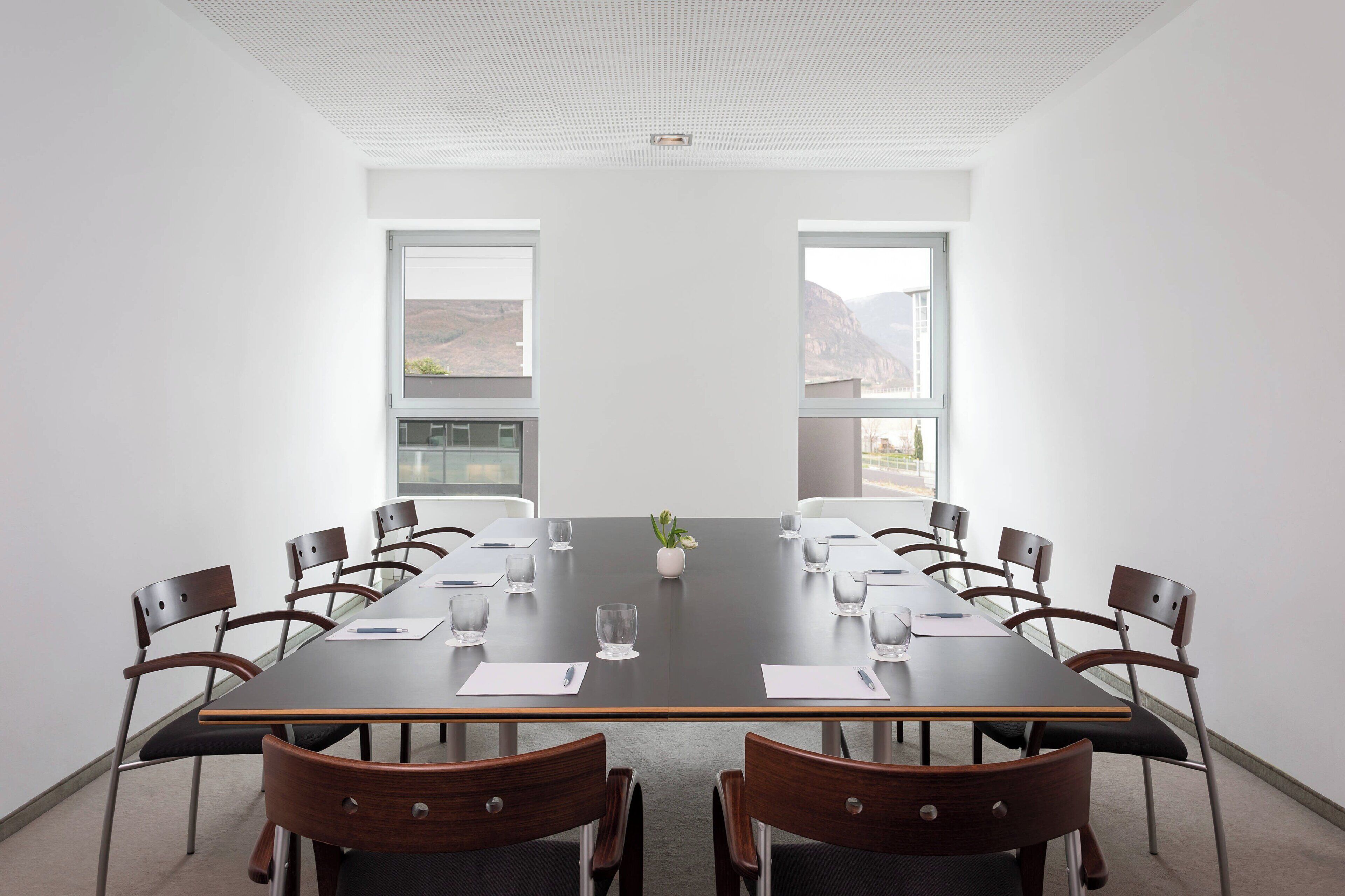 Ein Konferenzraum mit einem langen Tisch, Stühlen und großen Fenstern.