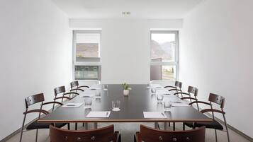 Ein Konferenzraum mit einem langen Tisch, Stühlen und großen Fenstern.
