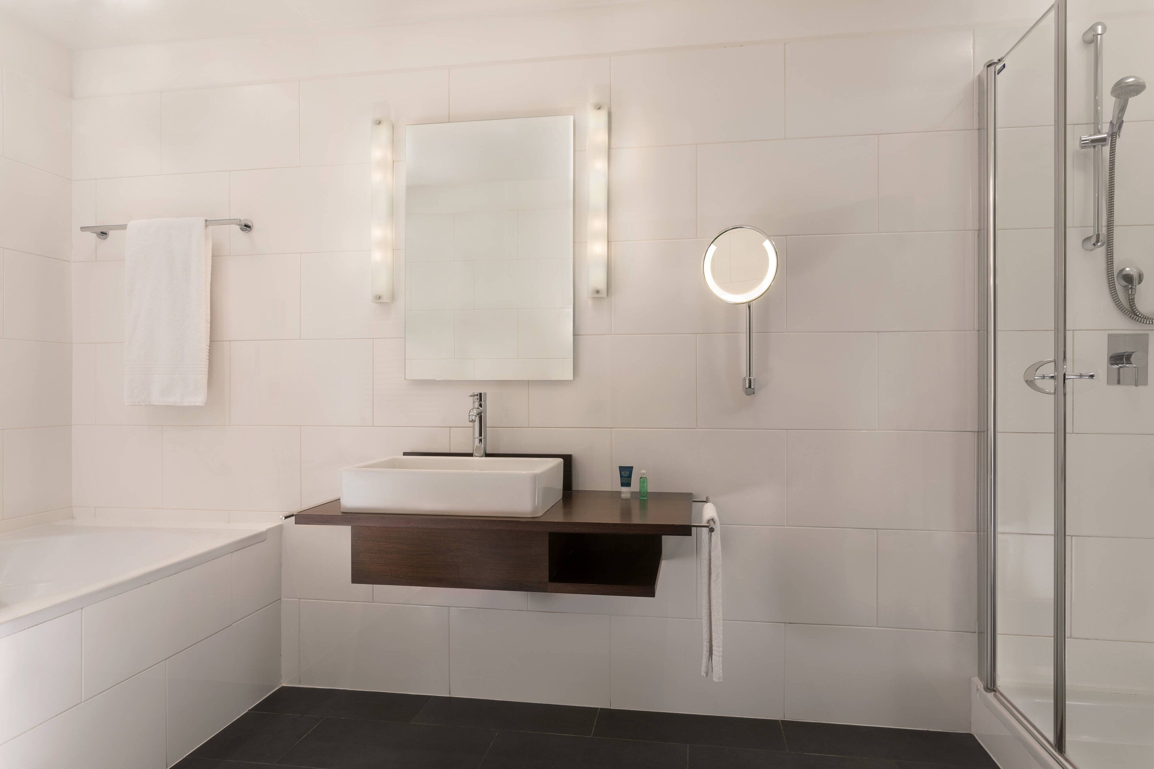 Un baño moderno con bañera, tocador con espejo y ducha con mampara de vidrio.