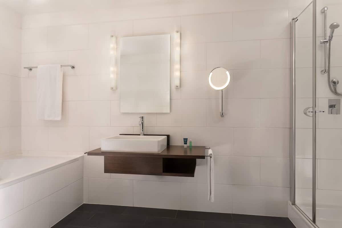 Un baño moderno con bañera, tocador con espejo y ducha con mampara de vidrio.