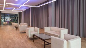 A modern lounge area with leather sofas, a glass coffee table, and a wooden floor. - Four Points by Sheraton Bolzano (Bolzano)