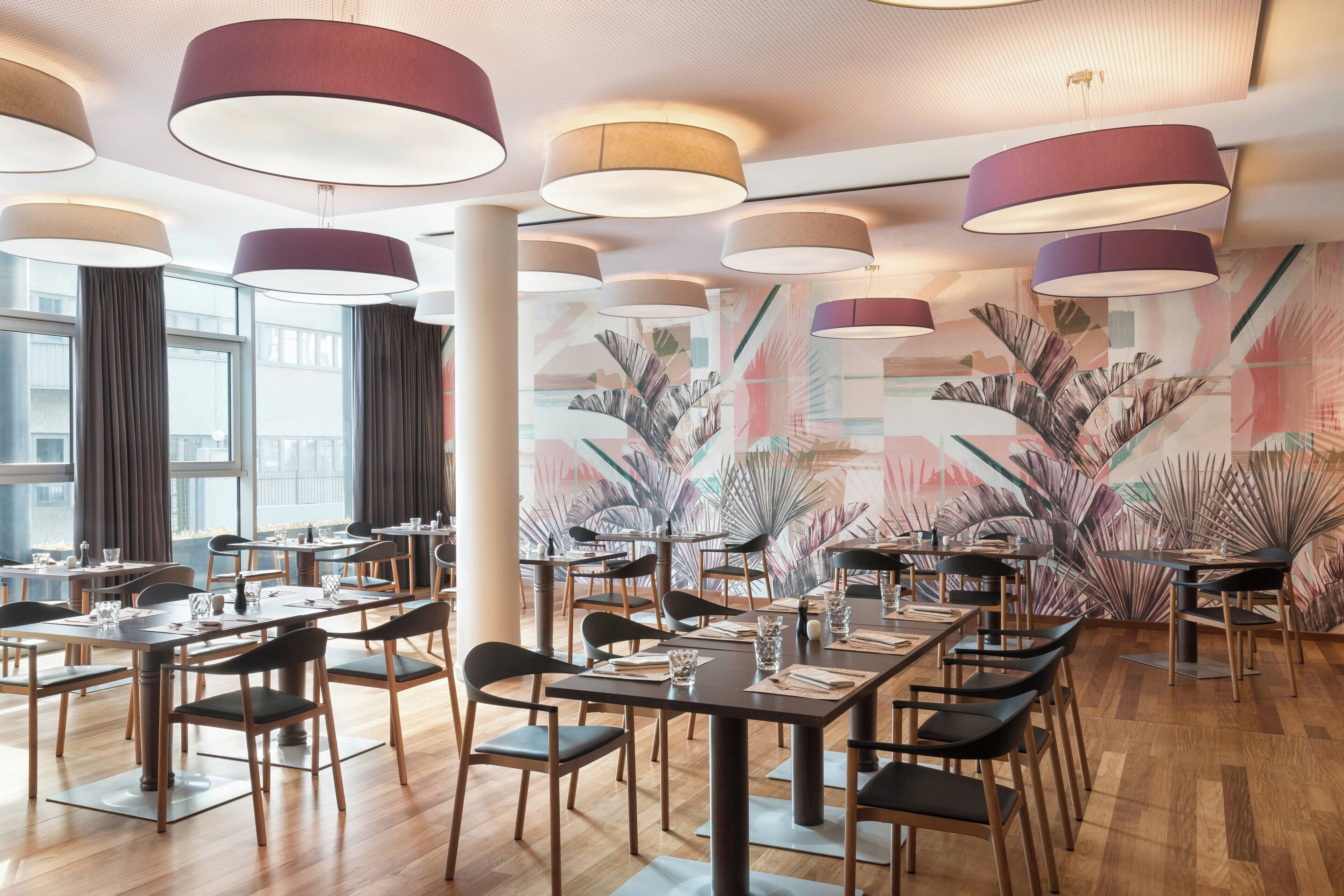 Een restaurantinterieur met meerdere tafels, stoelen en hangende lampen.