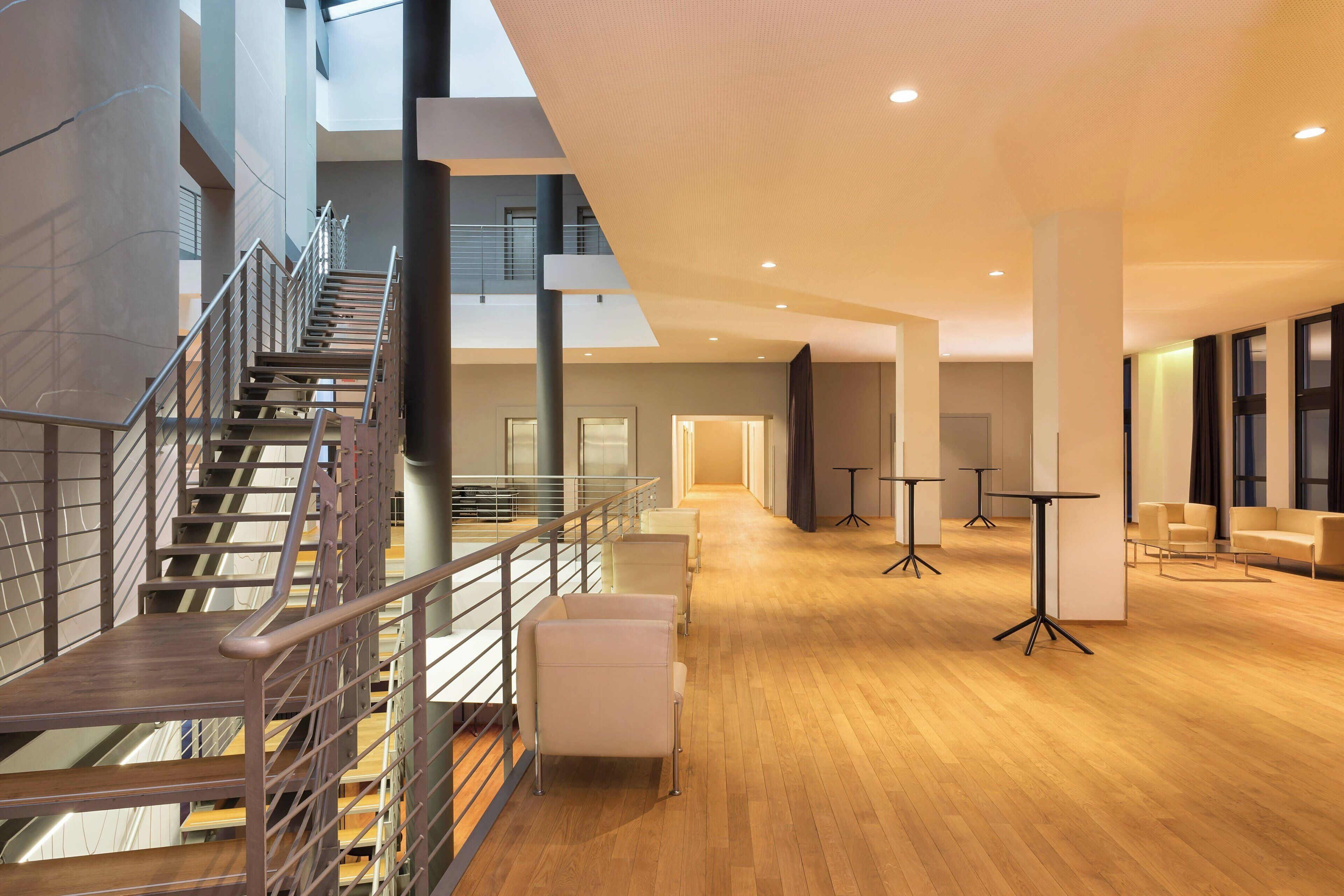 A modern interior with a staircase, seating area, and tables.