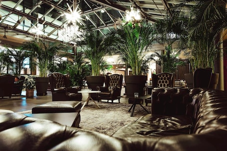 A spacious indoor area with leather sofas, armchairs, and a large potted plant.