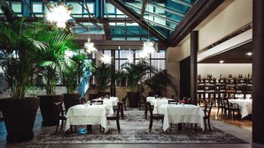 A spacious indoor dining area with multiple tables and chairs, large potted plants, and a high ceiling with natural light. - Four Points by Sheraton Bolzano (Bolzano)