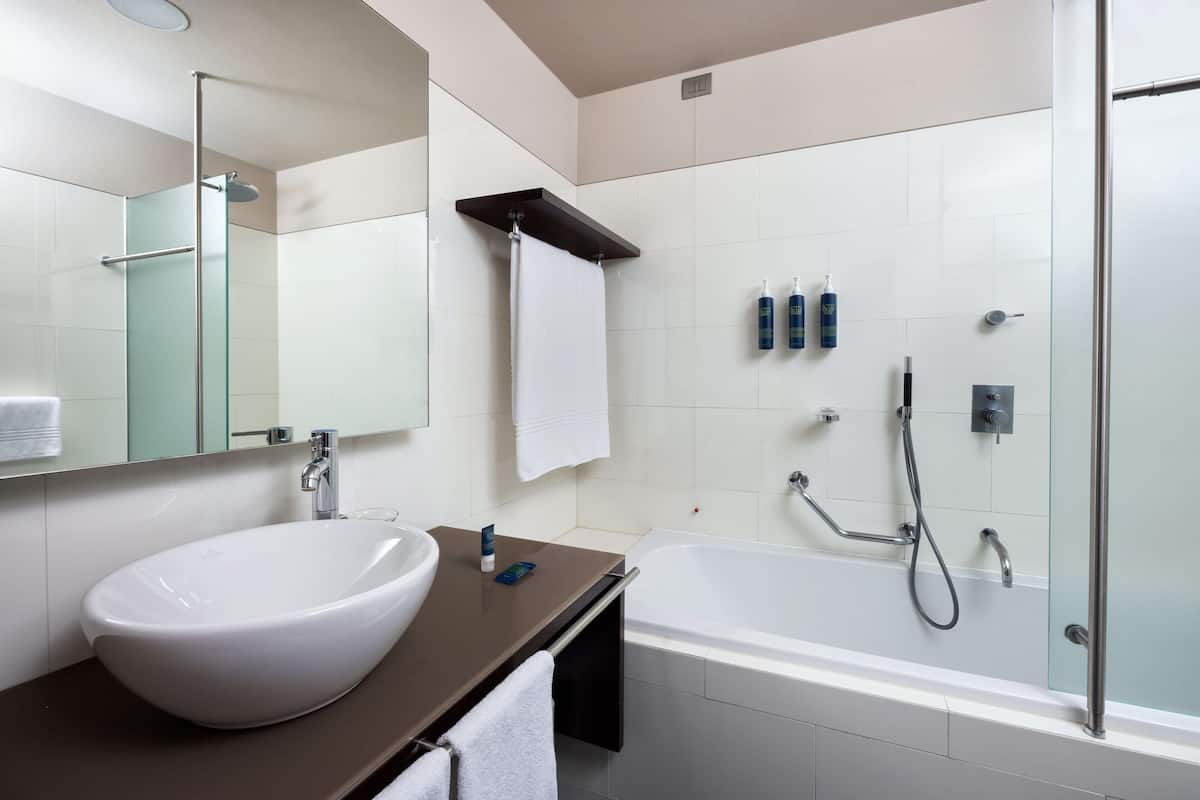 Un baño moderno con un lavamanos blanco, una bañera y un box de ducha de vidrio.