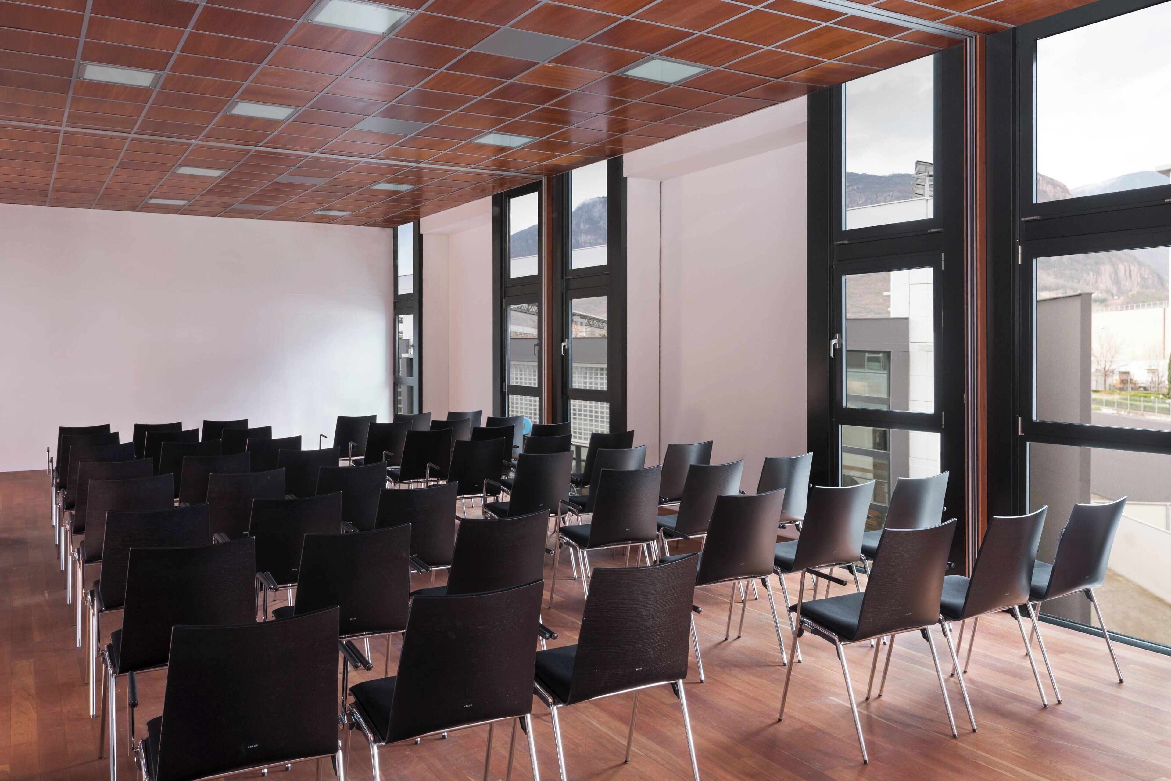 A conference room with rows of chairs, large windows, and a wooden ceiling.