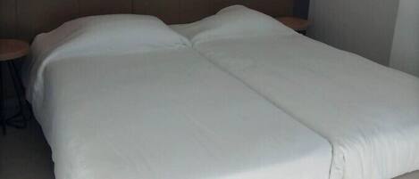 A modern hotel room with a large bed, a bedside table, and a wall-mounted light fixture.