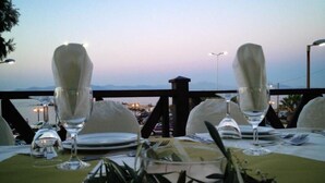 A table set for two with a view of the sea and mountains in the background.