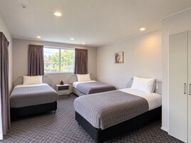 Una habitación de hotel con dos camas, una mesita de noche, un cuadro y un armario.