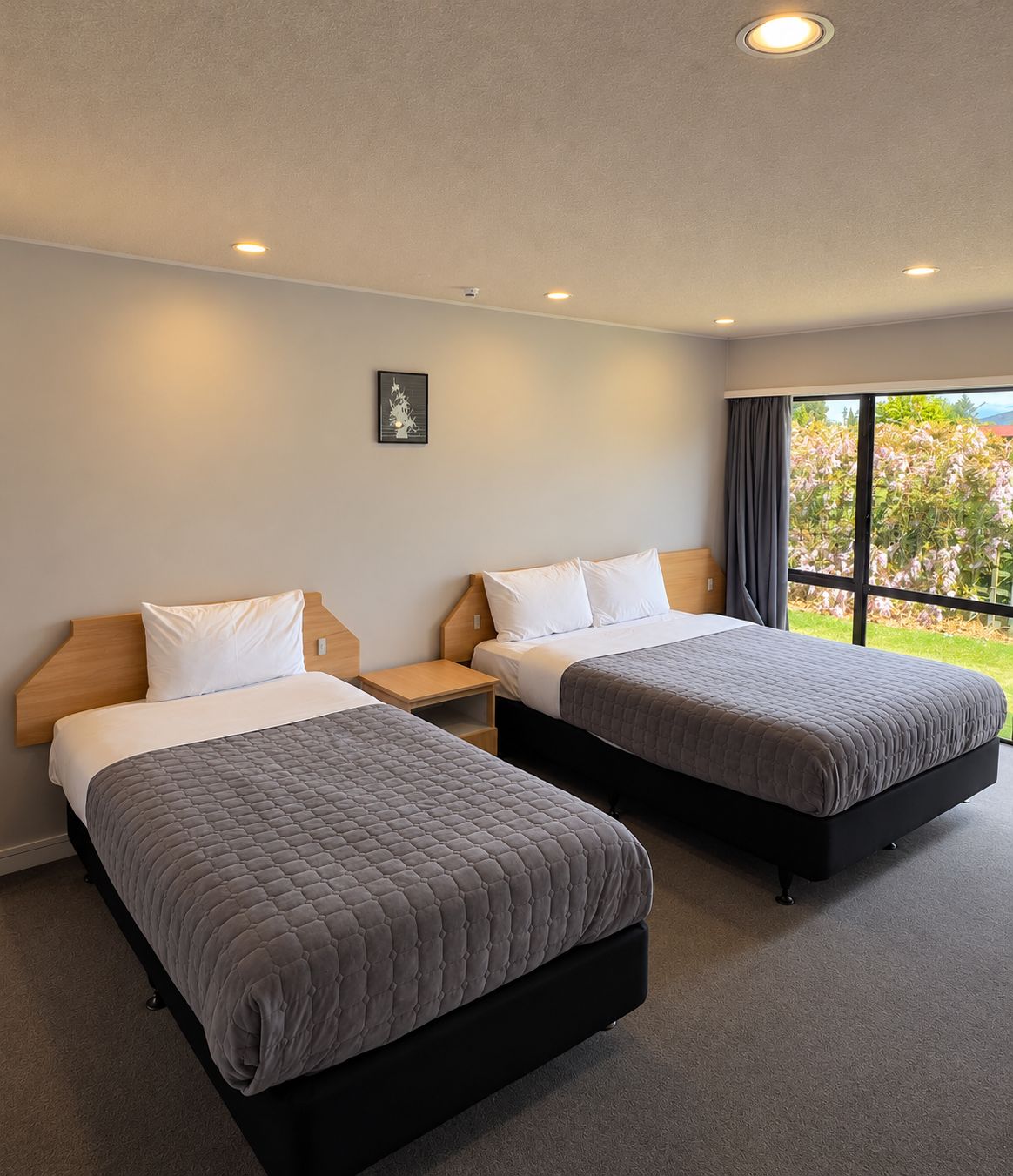 Ein Hotelzimmer mit zwei Betten, einem Nachttisch, einem kleinen Tisch und einem Bild an der Wand.