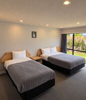 Una habitación de hotel con dos camas, una mesita de noche, una pequeña mesa y un cuadro en la pared.