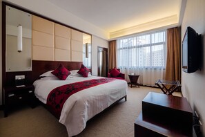 A hotel room with a large bed, a TV mounted on the wall, a small table, and a window with curtains. - Ruitai Hongqiao Hotel (Shanghai)