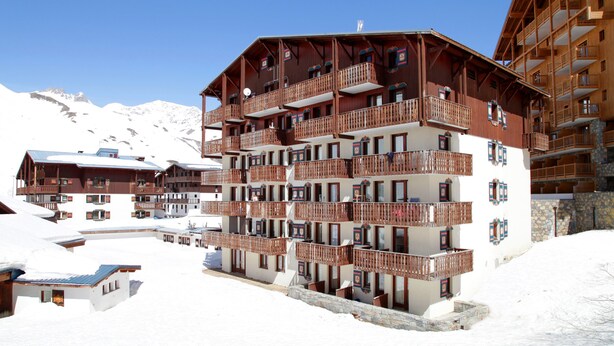 A multi-story hotel with balconies, a ski slope in the background, and snow-covered surroundings. - Résidence Val Claret (Tignes)