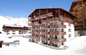 A multi-story hotel with balconies, a ski slope in the background, and snow-covered surroundings. - Résidence Val Claret (Tignes)
