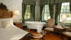 A classic bedroom with a large bed, a clawfoot bathtub, and two chairs. - Cameron Estate Inn & Restaurant (Mount Joy)