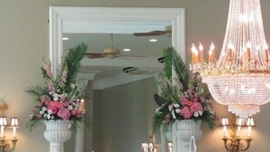 A room with a white fireplace, two large flower arrangements, a chandelier, and wall sconces. - Cameron Estate Inn & Restaurant (Mount Joy)