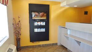 A reception area with a blackboard displaying a cooking video, a vase with dried flowers, and a tiled floor. - Americas Best Value Inn Goldsboro (Goldsboro)