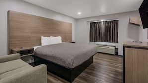 Une chambre d’hôtel moderne, dotée d’un grand lit, d’un bureau, d’une chaise, d’une télévision et d’une fenêtre avec des rideaux.