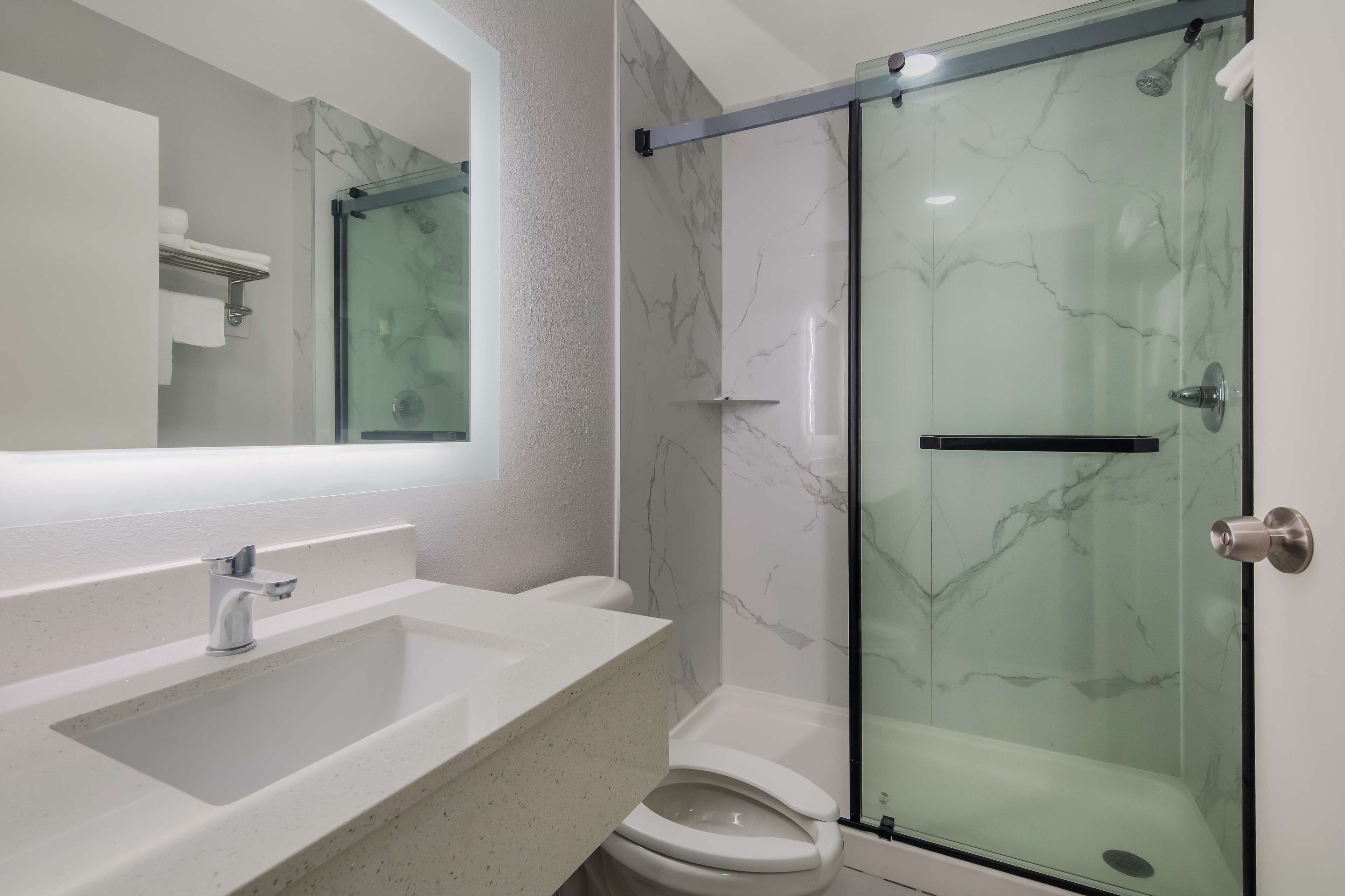 Un baño moderno con ducha de vidrio, lavamanos blanco y un inodoro.