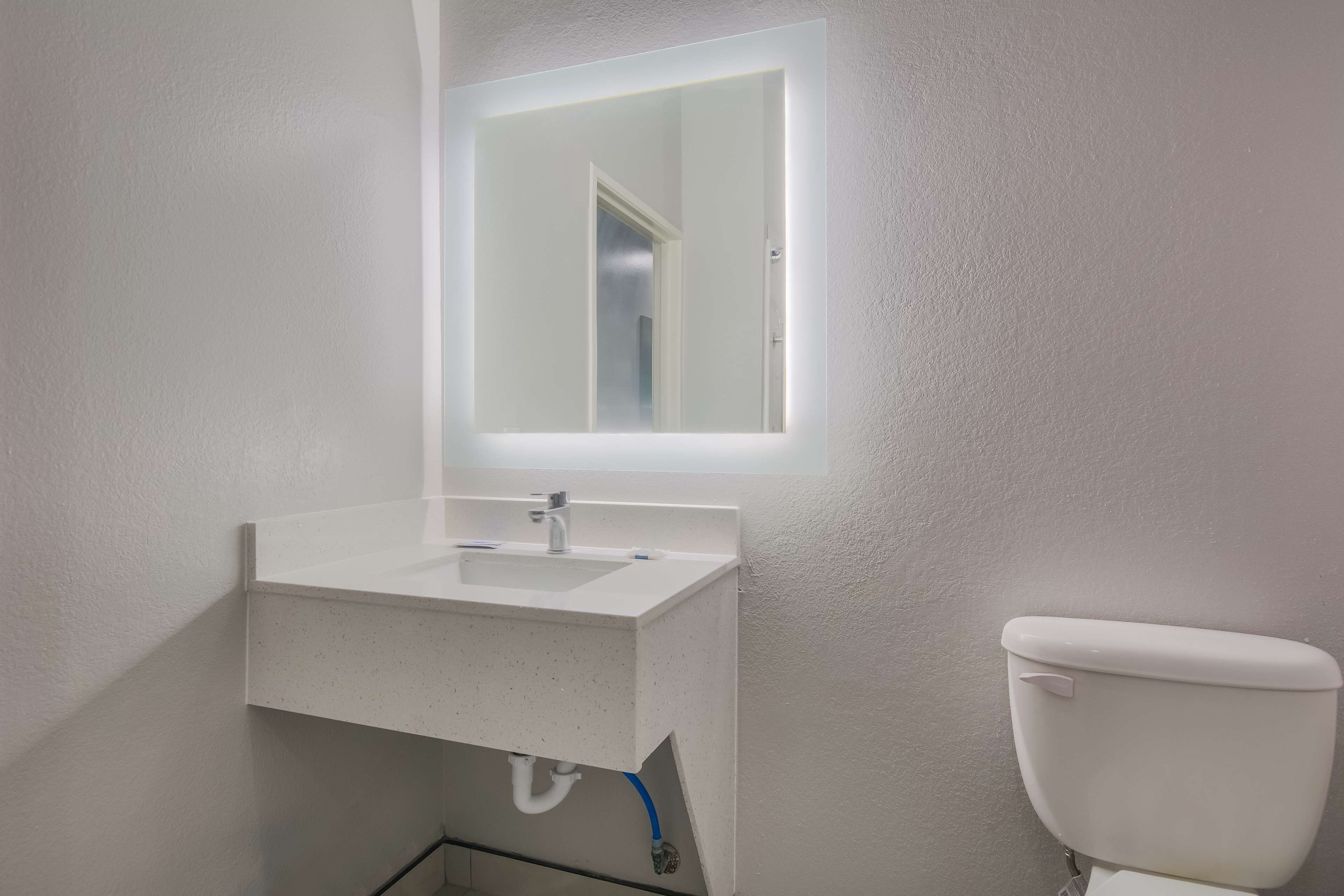 Un baño con lavamanos blanco, un espejo y un inodoro.