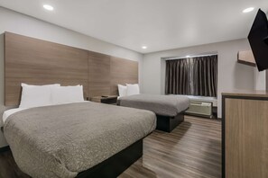 A modern hotel room with two beds, a desk, a flat-screen TV, and a window with curtains.